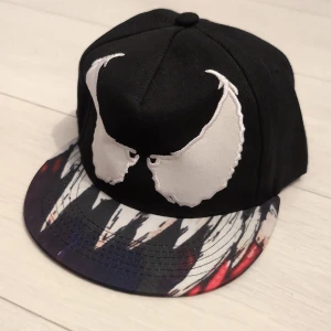 Keps med brodering och tryck - Keps med ögon och tänder liknande ett monster.