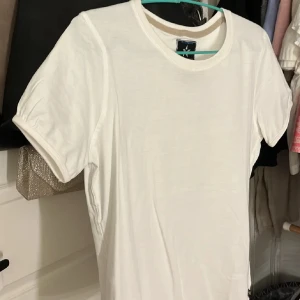 Vit t-shirt i bomull - Säljer en vit t-shirt från Fusion Wear i storlek M. T-shirten har klassisk rund hals, korta ärmar och är gjord i mjuk bomull. Enkel och stilren design utan mönster eller detaljer, perfekt för dig som gillar cleana plagg.