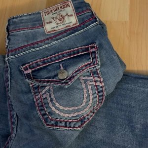 True Religion jeans med rosa sömmar - Säljer ett par blå true religion jeans med rosa sömmar. Säljer då storleken är för stor för mig. Nypris 2.300kr. Byxorna finns ej kvar i sortimentet och inte säkert att de kommer tillbaka igen. Pris kan diskuteras. 