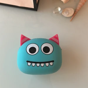 Monster-design hörlursfodral - Roligt och färgglatt fodral för trådlösa hörlurar, med monsteransikte och öron. Passar AirPods eller liknande små hörlurar. Fodralet har dragkedja och är i gott skick med mindre yttre slitage. Perfekt för att skydda och förvara dina hörlurar med stil.