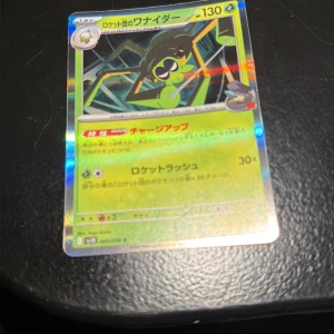 ロケット団のワナイダー - Cool och glittrande japansk Pokémon-kort med en spindel-liknande karaktär från Team Rocket. Perfekt för samlare och Pokémon-fans som vill ha något unikt i sin samling. Kortet har snygg design och är i fint skick – ett måste för dig som älskar Pokémon!