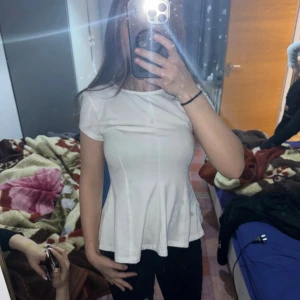 Vit blus med utsvängd midja Gina Tricot - Säljer en vit blus från Gina Tricot i storlek S. Toppen har rund halsringning, korta ärmar och en figurnära passform som svänger ut vid midjan för en snygg siluett. Materialet är mjukt och skönt, perfekt för dig som gillar enkel och clean stil.