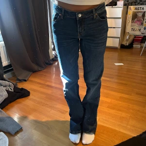  blå jeans bootcut - Säljer ett par klassiska  jeans i mörkblå tvätt med bootcut-snitt. Jeansen har fem fickor, knappgylf och normal passform. Materialet är slitstarkt denim och midjan är midwaist. Perfekta för dig som gillar tidlös stil och vill ha ett par jeans som funkar till allt.