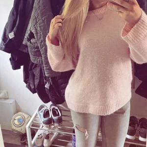 Ljusrosa stickad tröja - Supermjuk och fluffig ljusrosa stickad tröja med rund halsringning och ribbade muddar. Tröjan har en loose passform och långa ärmar, perfekt för mysiga dagar. Enkel och stilren design som är lätt att matcha med jeans eller kjol.