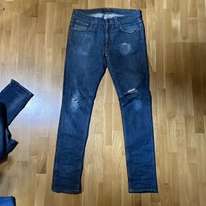 Mörkblå nudie jeans - Nudie lean dean w31L34. Riktigt fräscha med schyssta slitningar! Midja ca 40cm längd 100cm! Skriv pm vid frågor!