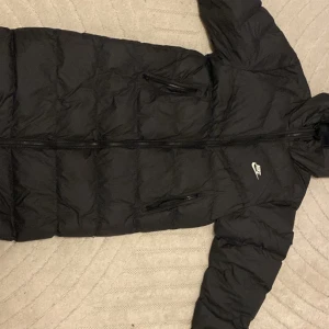 Svart lång Nike Jacka - Svart lång pufferjacka från Nike med luva. Byte tas imot också
