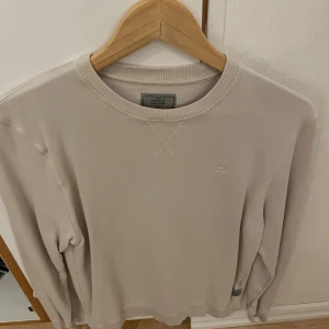 Beige långärmad tröja The Perfect Sweater - Snygg beige långärmad tröja från The Perfect Sweater med rund hals och diskret broderad logga på bröstet. Tröjan har ribbade muddar vid hals, ärmslut och nederkant. Storlek XS men passar minde S också.