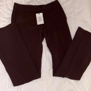 Bruna kostymbyxor från Bik Bok - Snygga bruna kostymbyxor från Bik Bok med klassisk rak passform och pressveck. Byxorna har bälteshällor, sidofickor och är tillverkade i ett mjukt material som ger en stilren look. Perfekta för dig som gillar en clean och dressad vibe.