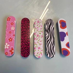 Färgglada nagelfilar med mönster - Fem nagelfilar i olika färger och mönster: blommigt rosa, leopardmönstrad i svart och cerise, vit med små rosa blommor, svartvit zebramönstrad och vit med lila och orange hjärtan. Perfekt för att fixa naglarna med stil.
