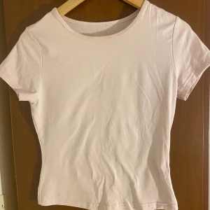 Ljusrosa t-shirt från SHEIN - En basic ljusrosa t-shirt från SHEIN med rund halsringning och korta ärmar. Modellen är figurnära och enkel, perfekt att matcha med jeans eller kjol. Tillverkad i mjuk bomullsmix för en skön känsla hela dagen.