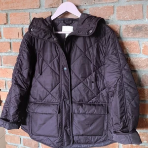 vinröd quiltad pufferjacka H&M XS - Quiltad pufferjacka från H&M i vinrött med huva och stora fickor framtill. Jackan har lång ärm, tryckknappar och snygg oversized passform. Perfekt för kyliga dagar och har ett coolt rutmönster över hela jackan.