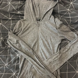 Grå ribbad hoodie från BikBok - Grå ribbad hoodie från BikBok i storlek S. Tröjan har dragkedja framtill, huva och långa ärmar. Perfekt för en chill och avslappnad stil. Materialet är mjukt och stretchigt, vilket gör den superbekväm att bära.