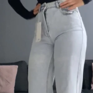 Ljusblåa wide jeans med slits - Säljer ett par ljusblåa jeans med hög midja och wide fit. Jeansen har slits nertill vid bensluten och klassiska fem fickor. Perfekta för dig som gillar en avslappnad och trendig look.
