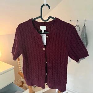 Vinröd kabelstickad kofta H&M - Säljer en vinröd kabelstickad kofta från H&M i nyskick, helt ny MED prislapp😍 superfin nu till hösten, nypris 200kr men den är slutsåld nästan överallt😇