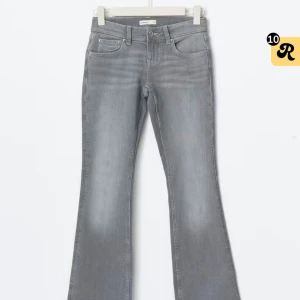 Grå bootcut jeans - Snygga grå jeans med bootcut passform och klassisk femficksdesign. Jeansen har ljusa slitningar och dekorativa sömmar på bakfickorna. Använt 1 gång. Ny pris 400kr 