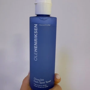Ole Henriksen Glow2OH Dark Spot Toner - Glow2OH Dark Spot Toner från Ole Henriksen i en snygg blå plastflaska med vitt lock. Innehåller 190 ml och är berikad med AHA-syror som hjälper till att jämna ut hudtonen och reducera mörka fläckar. Perfekt för dig som vill ha glow och fräsch hy. Använt fåtal gånger. Annars helt ny 