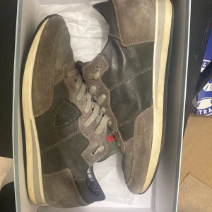 Philippe model trainers - Säljer ett par snygga bruna sneakers från Philippe Model med detaljer i mocka och skinn. Skorna har snörning, rund tå och en platt sula. Insidan är vadderad för extra komfort och yttersulan är i gummi. Perfekt för dig som gillar stilrena och klassiska sneakers.