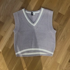 Ljuslila stickad väst från H&M Divided - Superfin ljuslila stickad väst från H&M Divided i storlek XS. Västen har v-ringning och vita ränder vid halsringning och nederkant. Perfekt att styla över en skjorta eller t-shirt för en trendig look.alldrig anndvänd