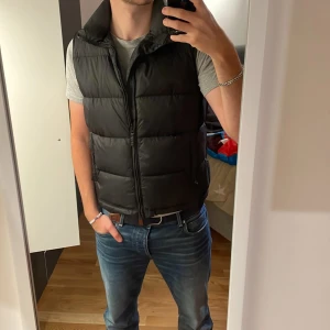 Svart dunväst - Säljer en svart dunväst i mycket bra skick. Den har en dragkedja framtill och är perfekt för höst, vinter och vår. Västen har en normal passform och är riktigt skön att ha på sig. Perfekt för att hålla värmen utan att bli för varm. Passar både till vardags och lite mer avslappnade tillfällen. Sjuukt fet och passar till allt🤙🤙🫵