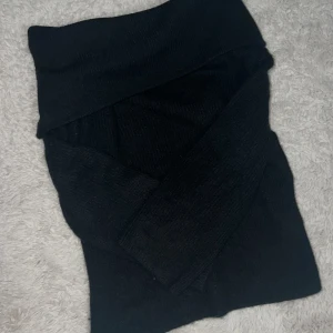 Svart stickad tröja nedvikt vid axlarna - Mysig svart stickad tröja med nedvikt krage vid axlarna. Tröjan har lång ärm och är perfekt för kyligare dagar. Enkel och stilren design som passar till det mesta. Snygg att styla med jeans eller kjol.