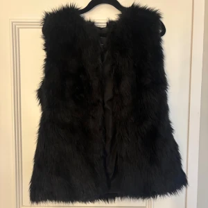 Svart pälsväst från Bershka - Snygg svart pälsväst från Bershka med en rak passform. Västen är helsvart och i fejkpäls. Säljer då jag har en liknande och bara använd en gång☺️