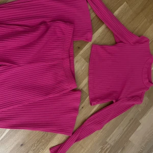 Ribbad rosa långärmad tröja tillsammans med matchande byxor Shein XS - Säljer en ribbad långärmad tröja och matchade byxor från Shein i en snygg rosa färg. Tröjan är croppad och har en rund hals. Byxorna är lite pösiga men sitter bra. Materialet är mjuk och stretchig polyester med lite elastan, vilket gör den skön att bära. Perfekt att matcha med ett par fina klackar.