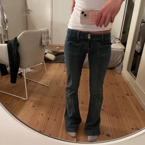Blå bootcut jeans med fickdetaljer - Snygga blå jeans med lowwaist bootcut passform och låg midja från Nelly.💕 De är tyvärr  lite slitna längst ner men annars är de i väldigt bra skick. Original pris är 699 kr