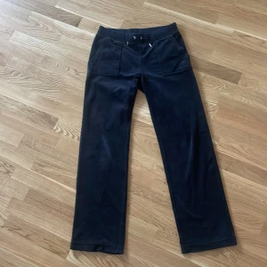 Svarta  Juicy Couture byxor i m - Svarta mjukisbyxor från Juicy Couture i mjuk velour med raka ben, snörning i midjan och stora fickor fram. Baktill finns två fickor med knappar. Har använt dom max 4 gånger.vill gärna få sålt fort , kan diskutera pris .kommer även sälja koftan men har inte lagt upp den än 
