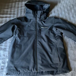 Svart skaljacka från Peak Performance - Säljer en svart skaljacka från Peak Performance med huva och hel dragkedja framtill. Jackan har diskret logga på bröstet och är tillverkad i ett slitstarkt syntetmaterial. Perfekt för utomhusaktiviteter och vardagsbruk. Nypris: 2845kr från Zalando
