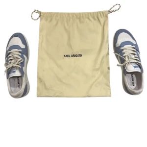 Axel Arigato blåvita sneakers - Säljer ett par stilrena sneakers från Axel Arigato i ljusblått och vitt. Skorna är storlek 43. Medkommer dustbag då jag slängde boxen till dem! Hör av er vid intresse 