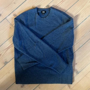 Blå stickad tröja från Uniqlo XS - Jag säljer en blå stickad tröja från Uniqlo i storlek XS. Tröjan har rund halsringning, ribbade muddar vid ärmslut och nederkant samt långärmad passform. Tröjan är i bra skick men har ett litet hål på baksidan. Perfekt för kyliga dagar och enkel att matcha med jeans.