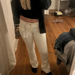 Vita bootcut jeans med hög midja - Säljer ett par oanvända vita bootcut jeans från weekday med lowwaist midja och klassiska fickor både fram och bak. Jeansen har en snygg passform som sitter tajt upptill och släpper ut vid benen. Perfekta för dig som vill ha en fräsch och trendig look.