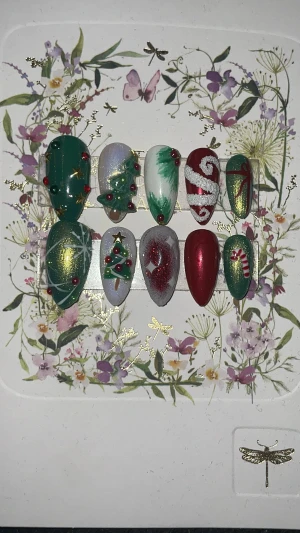 Juliga press-on naglar - Säljer ett set med 10 handgjorda press-on naglar i olika storlekar, dekorerade med julmotiv som granar, polkagrisar, glitter och stjärnor. Färgerna är grönt, rött, vitt och guld med detaljer i 3D och glansig finish. Naglarna har en almond form och passar perfekt för dig som vill ha extra festliga naglar. STORLEK: S. skriv om annan storlek behövs.