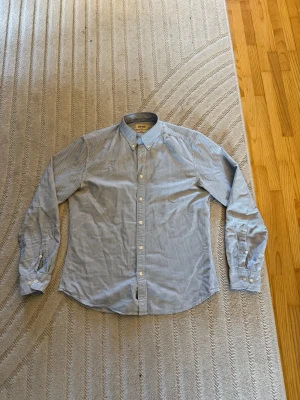 Blårandig skjorta från East West - Snygg blårandig skjorta från East West med klassisk krage och vita knappar hela vägen. Slim fit-modell som sitter schysst på kroppen. Tillverkad i mjuk bomull och har långa ärmar med knapp vid manschetten. Perfekt för dig som gillar stilrena och fräscha skjortor.