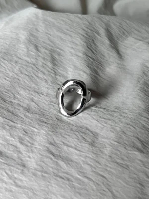 Assymetrical Oval - Justerbar ring i rostfritt stål med en ren, asymmetrisk ovalform. Minimal och modern.