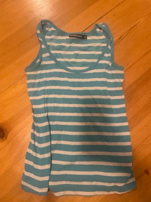 Randig linnetopp från Point Zero - Säljer en fräsch randig linnetopp från Point Zero i storlek 38. Toppen har breda axelband och ärmlös design, med turkosa och vita horisontella ränder. Perfekt för varma dagar och chill stil. Mjuk och skön bomullskänsla.