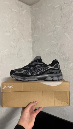 ASICS GEL-NYC svarta sneakers - ASICS GEL-NYC sneakers i svart och grått med meshpaneler och syntetdetaljer. Skorna har en chunky sula, snörning och klassisk ASICS-logga på sidan. Perfekta för dig som gillar sportig och modern stil. Storlek 44 men känns som 43 och är helt nya. 