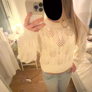 Vit stickad tröja från Lindex - Säljer en vit stickad tröja från Lindex i storlek S. Tröjan har ett snyggt hålmönster, ribbad hals och muddar samt långärmad modell. Den är lite croppad och har en mjuk, cozy vibe som passar perfekt till jeans eller kjol.