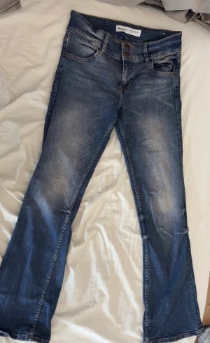 Blå bootcut jeans från Bershka - Snygga blå jeans från Bershka i bootcut-modell. Jeansen har en tvättad look med ljusare partier och är tillverkade i jeansmaterial. Köpte de i spanien förra året men aldrig använt de. 