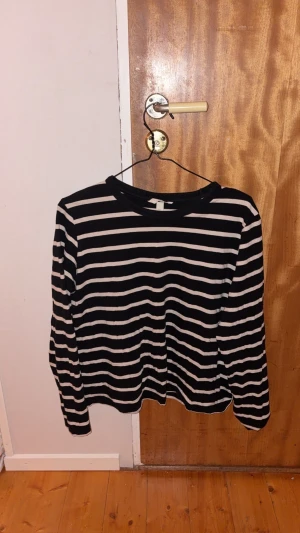 Svartvit randig långärmad tröja - Svart och vit långärmad tröja från H&M med klassiskt horisontellt randigt mönster. Rund halsringning och mjukt bomullsmaterial som är skönt mot huden. Perfekt för dig som gillar enkel och stilren streetstil.
