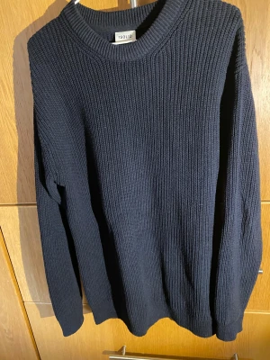 Mörkblå stickad tröja från Solid - Säljer en mörkblå stickad tröja från Solid med grov ribbad struktur och rund hals. Tröjan har långärmade ärmar och en klassisk, enkel design som funkar till många stilar. Perfekt för kyliga dagar och enkel att matcha med jeans eller chinos.