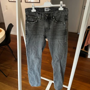 Grå jeans från 157 med slitna detaljer - Grå jeans från 157 med klassisk femficksdesign och slitna detaljer vid benslut. Jeansen har en rak passform och är tillverkade i bomullsmaterial. Snyggt tvättad look som ger en cool vibe och passar perfekt till sneakers eller boots.