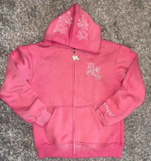 Decrece Sweden set Rosa Melange  - Decrese Sweden set Rosa Melange  Unisex hoodie + byxor i mjuk bomull med stretch. Vit broderad logga och detaljer. Byxor: midja 30–42 cm, innerben 68 cm, ytterben 94 cm, 2 fram- och 2 bakfickor. Hoodie: axel 48 cm, bröst 50 cm, längd 64 cm, ärm 60 cm. Storlekar XS–XL.