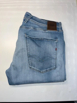 Replay Anbass jeans  - Säljer ett par Replay Anbass jeans i ljusblå tvätt med snygga slitningar och klassiska fem fickor. Modellen är slim fit med normal passform och raka ben. Midja 45cm, längd 109cm. JAG SKICKAR EJ FLER BILDER NÄR JAG BÄR JEANSEN! för storleksguide hänvisar jag till måtten och för bättre inblick i passformen rekommenderar jag att googla på modellnamnet. kolla måtten noggrant :) 51