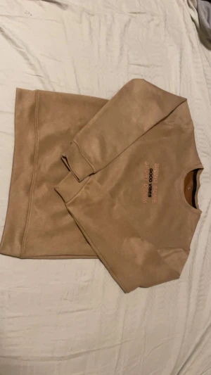 Beige sweatshirt med tryck, storlek L - Snygg beige sweatshirt från Sport Denim i storlek L. Tröjan har ett tryck på bröstet med texten 'BRING SOME GOOD VIBE8 SPORT DENIM'. Rund hals, långa ärmar och mjukt material som känns skönt mot huden. Perfekt för chill dagar och enkel att matcha med jeans.