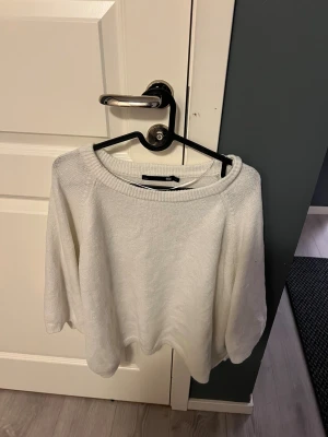 Vit stickad tröja med rund hals - Snygg vit stickad tröja från 15Z med rundad hals och avslappnad passform. Perfekt för dig som gillar enkel och stilren design. Tröjan har långa ärmar och mjukt material som känns skönt mot huden. Passar till jeans eller kjol för en chill look.