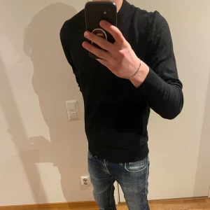 Svart stickad tröja  - En stilren svart stickad tröja med rund hals och långa ärmar. Tröjan har en normal passform och ribbade muddar vid ärmslut och nederkant. Perfekt för dig som gillar enkel och clean stil. Skriv vid funderingar🤝