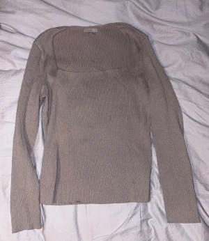 Beige/grå ribbad långärmad topp H&M - Säljer en beige/grå ribbad långärmad topp från H&M med fyrkantig ringning. Toppen är figurnära och har en stilren, enkel design som passar perfekt till jeans eller kjol. Materialet är mjukt och stretchigt för en bekväm känsla.