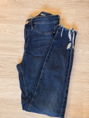 Mörkblå Molly jeans med slitningar - Snygga mörkblå jeans från Molly med trendiga slitningar vid knäna och fransad kant. Klassisk femficksmodell med knapp och dragkedja i midjan. Jeansen har en smal passform och är tillverkade i stretchigt denim för extra komfort.