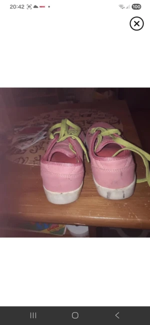 Rosa sneakers med limegröna snören - Säljer ett par snygga rosa sneakers med limegröna snören och vit sula. Skorna har rund tå och är dekorerade med diskreta mönster i materialet. Perfekta för dig som vill sticka ut med färg på fötterna.